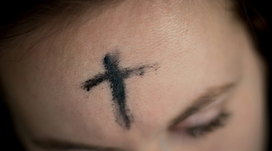 a closeup of a cross of ashes on a person's forehead